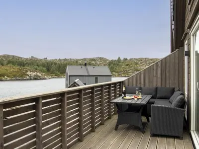 a patio with a table and a couch on a balcony at Holiday Home Brosme by Interhome in Bømlo