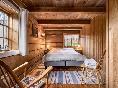 a bedroom in a log cabin with a bed and two chairs at Chalet Eiketun by Interhome in Olden