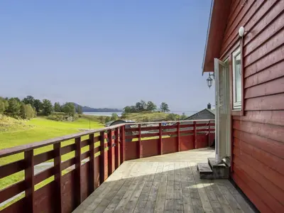 a red house with a wooden fence next to a building at Holiday Home Fjordglytt by Interhome in Onarheim