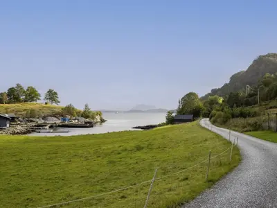 a road next to a grassy field and a body of water at Holiday Home Fjordglytt by Interhome in Onarheim