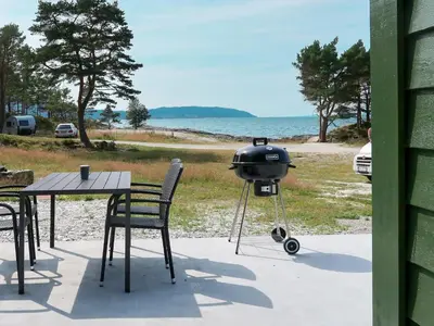 a grill sitting on a table next to a table with chairs at Holiday Home Nesholmen by Interhome in Leirvik