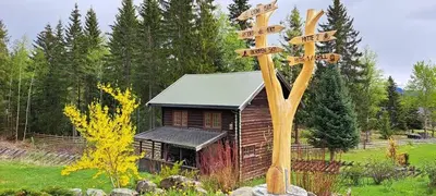 a wooden sign with arrows on it next to a cabin at Ønskedrømmen hytteutleie in Brandbu