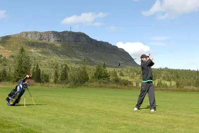 a man swinging a golf club in a field at Skeikampen Servicesenter in Svingvoll