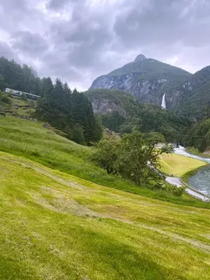 a green field with a river and a mountain at Gjørven Hytter in Flåm