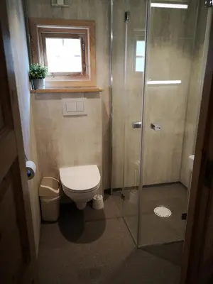 a bathroom with a toilet and a shower with a window at Trollveggen Camping in Åndalsnes