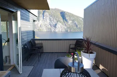 a balcony with a table and chairs and a view of the water at Fjord View Apartment in Stranda