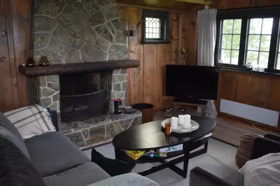 a living room with a stone fireplace and a tv at Skeikampen Booking in Svingvoll