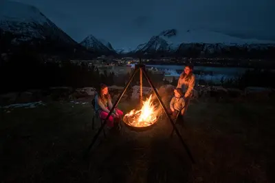 a group of three people sitting around a fire at Troll Fjordhytter in Syvde