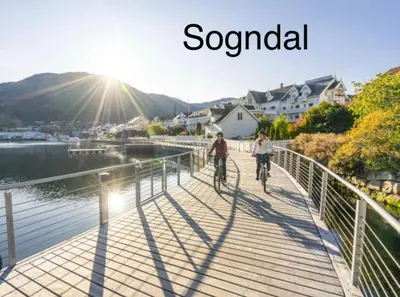 two people riding bikes on a bridge over a body of water at Two bedroom apartement in Sogndal