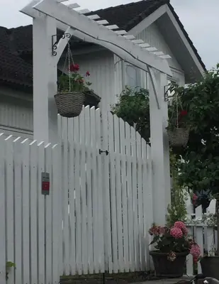 a white fence with baskets of flowers on it at The Gingerbread House in Lillehammer