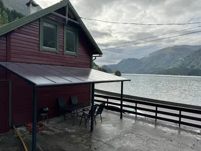 a house with a table and chairs next to a body of water at Vasstun Panorama in Odda