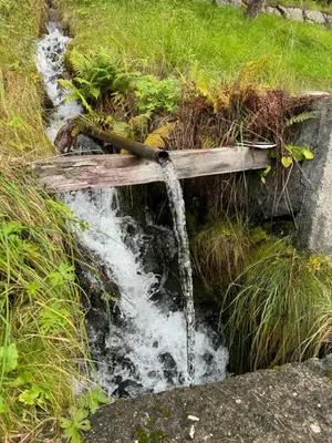 a stream of water coming out of a wooden bridge at Vasstun Panorama in Odda