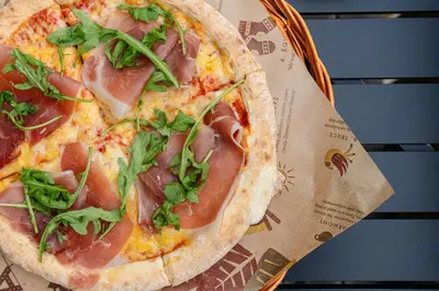 a pizza with ham and greens in a basket at Topcamp Rustberg - Hafjell in Hafjell