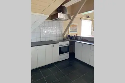 a kitchen with white cabinets and a black tile floor at Moldegaard Riding Lodge in Moldegard