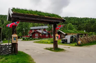 a building with a grass roof with flags on it at Rondane River Lodge - Rondane Gjestegård in Enden