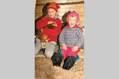 two children are sitting in a barn with a chicken at Skjerping gårdshus, in Lonevåg