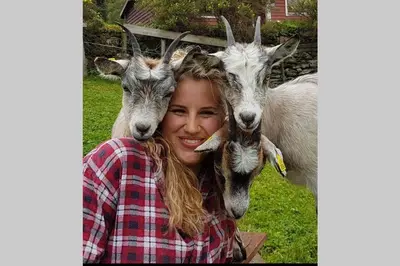 a woman is standing between two goats at Skjerping gårdshus, in Lonevåg