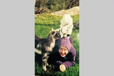 a woman is laying in the grass with two dogs at Skjerping gårdshus, in Lonevåg