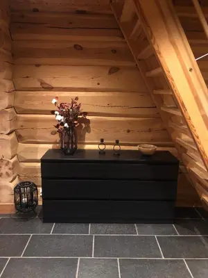 a black dresser with a vase of flowers on it at Hyggelig laftehytte på 140kvm med Ski-In/Out in Uvdal