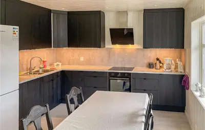 a kitchen with black cabinets and a table with chairs at Cozy Home In Etne With Wifi in Kyrping