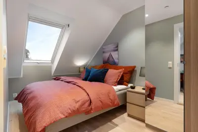a bedroom with a bed with an orange blanket and a window at Keyser Apartments 6 in Bergen