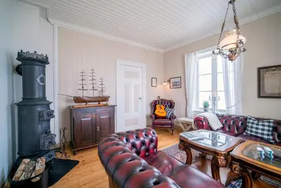 a living room with a leather couch and a wood stove at Flatflesa Fyr - by Classic Norway Hotels in Rindarøy