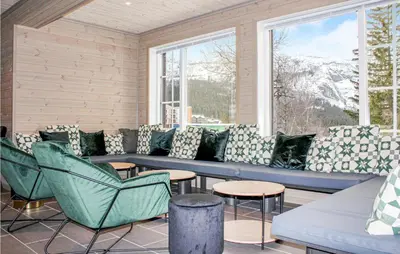 a porch with a blue couch and chairs and windows at Privat'n in Hemsedal