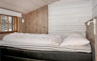 a large bed in a room with a wooden wall at Privat'n in Hemsedal