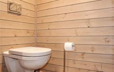 a bathroom with a toilet and a wooden wall at Privat'n in Hemsedal