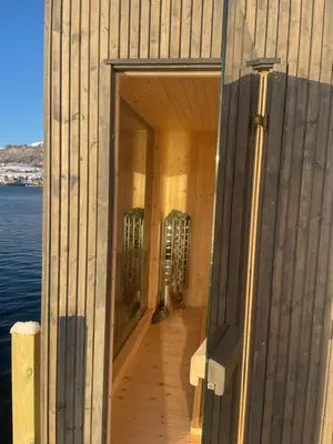 an open door of a building with the ocean in the background at Panoramaresort in Hardangerfjorden leilighet i sjøkanten ved Hardangerfjorden for 7 personer boat , sauna,kajak, SUP for rent in Øystese