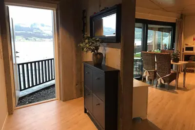 a living room with a view of the ocean from a balcony at Panoramaresort in Hardangerfjorden leilighet i sjøkanten ved Hardangerfjorden for 7 personer boat , sauna,kajak, SUP for rent in Øystese