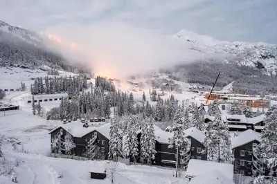 a snow covered mountain with a town in the foreground at Tinden in Hemsedal