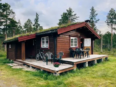 a log cabin with a deck and a table and chairs at Ryen Hytteutleie - Cottages in Røros