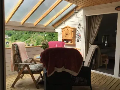 a room with a table and chairs on a deck at Iris Vedal in Nauste