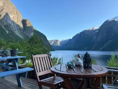 a table and chairs on a deck with a view of a lake at Iris Vedal in Nauste
