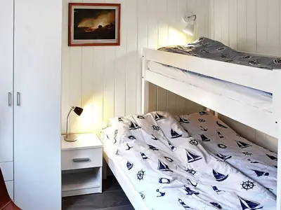 a bedroom with a bunk bed with blue and white sheets at 6 person holiday home in VATNE in Vatne
