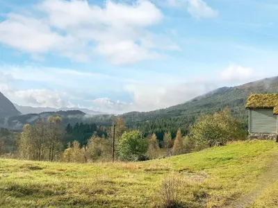 a barn in a field with mountains in the background at Secluded Mountain Retreat-By Traum in Vassenden