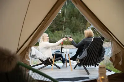 three women sitting in a tent with a bottle of wine at Toftemo Turiststasjon in Dovre