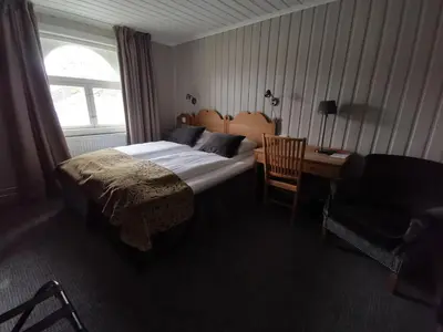 a bedroom with a bed and a desk and a chair at Sanner Hotell in Gran