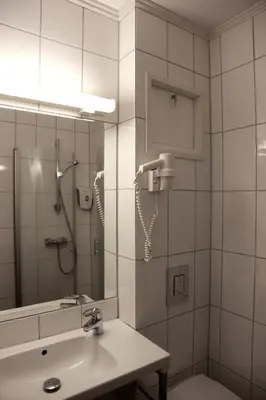 a bathroom with a shower and a sink and a mirror at Sanner Hotell in Gran