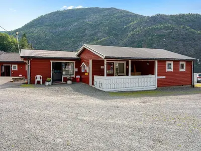 a small red building with a mountain in the background at Grimen Camping in Bergen