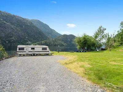 an rv parked on a gravel road next to a lake at Grimen Camping in Bergen