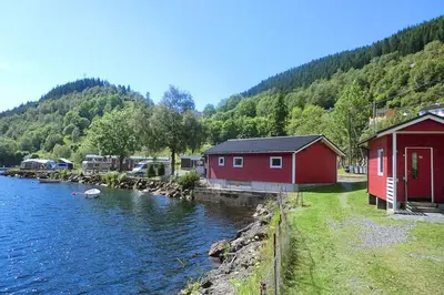 a couple of red buildings next to a body of water at Grimen Camping in Bergen