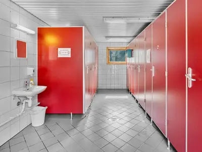 a bathroom with red stalls and a sink at Grimen Camping in Bergen