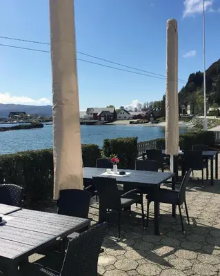a group of tables and chairs with a view of the water at Havly Bed & Breakfast in Hauge