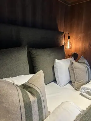 a bedroom with a bed with pillows and a lamp at Fjelleventyret gårdsovernatting in Skjåk