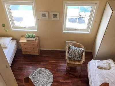 a bedroom with a bed and a chair and two windows at 6 person holiday home in Austrheim in Utkeila