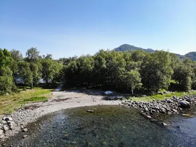 a river with trees on the side of it at Aursnes Hotell in Sykkylven