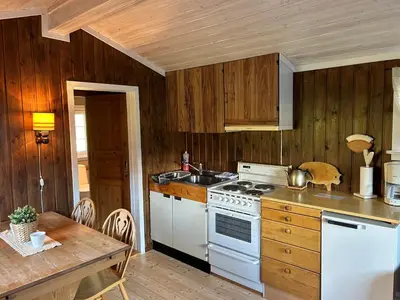 a kitchen with a white stove top oven next to a table at Harekroken in Tynset
