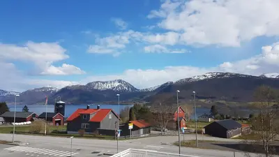 a town with snow covered mountains and a body of water at EIDE Gjestehus in Eide